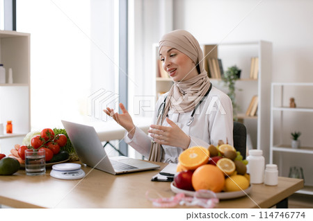 Muslim female making video call via wireless device at doctor's workplace. Muslim female making video call via wireless device at doctor's workplace. 114746774