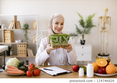 Muslim specialist in nutrition with hijab proposing modern addition to diet. Muslim specialist in nutrition with hijab proposing modern addition to diet. 114746820