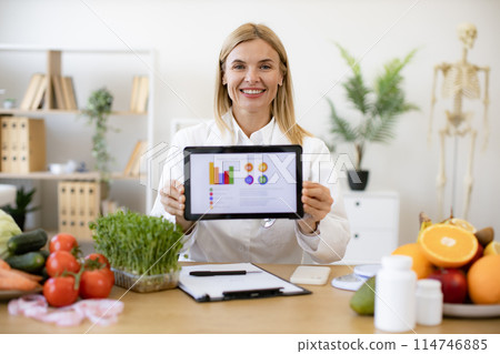 Caucasian female doctor holding tablet with charts of patients healthy diet. 114746885