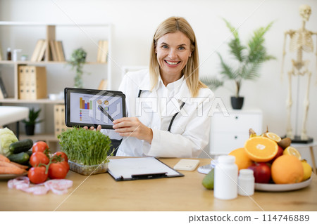 Happy female nutritionist presenting new app for calculating calorie. 114746889