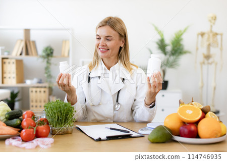 Caucasian lady in lab coat smiling at camera while demonstrating pills bottles. 114746935