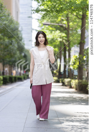 A woman in her 30s walking down the street A woman in her 30s walking down the street 114746976