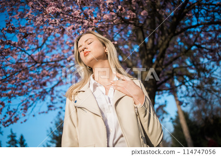 Woman with cherry flowers surrounded by blossoming trees copy space. Beauty and seasonal change and spring bloom season concept. 114747056
