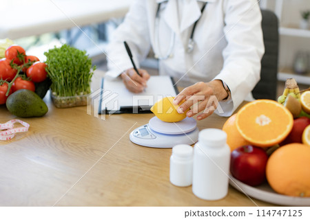 Close up of hands of female nutritionist doctor sitting at table. Close up of hands of female nutritionist doctor sitting at table. 114747125