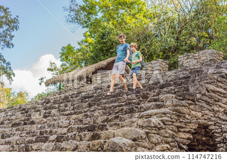 Dad and son tourists at Coba, Mexico. Ancient mayan city in Mexico. Coba is an archaeological area and a famous landmark of Yucatan Peninsula. Cloudy sky over a pyramid in Mexico Dad and son tourists at Coba, Mexico. Ancient mayan city in Mexico. Coba is an archaeological area and a famous landmark of Yucatan Peninsula. Cloudy sky over a pyramid in Mexico 114747216
