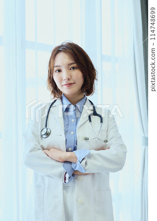 Female doctor standing by the window Female doctor standing by the window 114748699