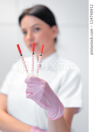 Cosmetologist woman showing three syringes in 114748912