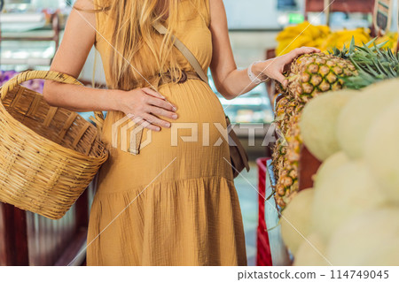 Pregnant woman holding belly while shopping in grocery store Pregnant woman buying organic vegetables and fruits at Mexican style farmers market Pregnant woman holding belly while shopping in grocery store Pregnant woman buying organic vegetables and fruits at Mexican style farmers market 114749045