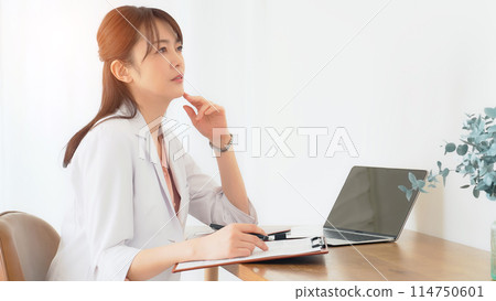 A middle-aged woman in a white coat thinking A middle-aged woman in a white coat thinking 114750601