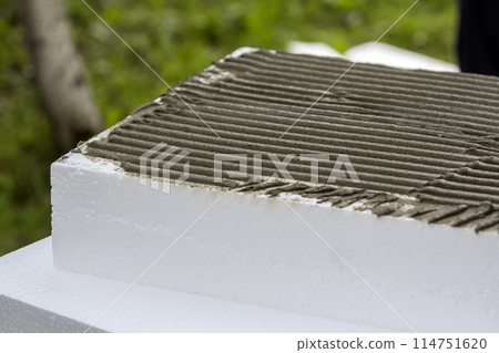 Close-up detail of stack of white rigid polyurethane styrofoam sheets with applied glue for house insulation. Modern technology, renovation, energy saving, alternative for mineral wool concept. Close-up detail of stack of white rigid polyurethane styrofoam sheets with applied glue for house insulation. Modern technology, renovation, energy saving, alternative for mineral wool concept. 114751620