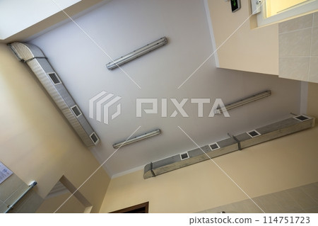 Industrial air duct ventilation equipment and pipe systems installed on building ceiling and walls. Comfortable workplace concept. 114751723