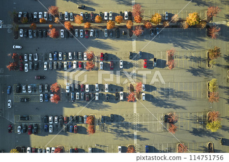 Aerial view of many colorful cars parked on parking lot with lines and markings for parking places and directions. Place for vehicles in front of a strip mall plaza 114751756