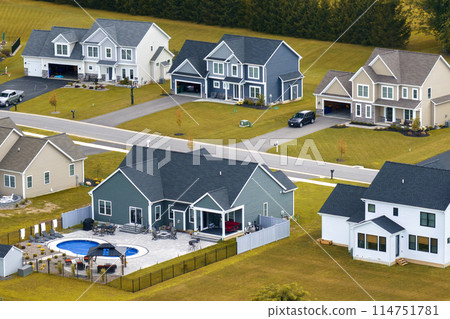 Upscale suburban homes with large backyards and green grassy lawns in summer season. Private residential houses in rural suburban sprawl area in Rochester, New York Upscale suburban homes with large backyards and green grassy lawns in summer season. Private residential houses in rural suburban sprawl area in Rochester, New York 114751781