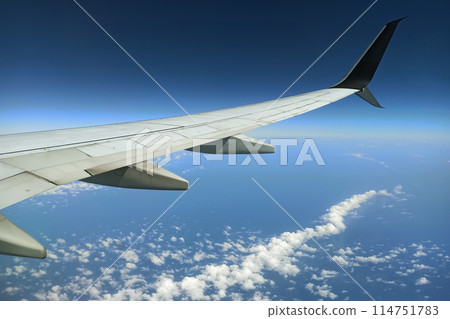 View through airplane window of commercial jet plane wing flying high in the sky. Air travelling concept View through airplane window of commercial jet plane wing flying high in the sky. Air travelling concept 114751783