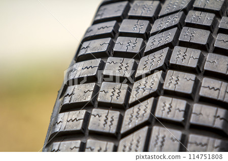 Close up detail of new black rubber car tire protector, selective focus, on copy space background. Close up detail of new black rubber car tire protector, selective focus, on copy space background. 114751808
