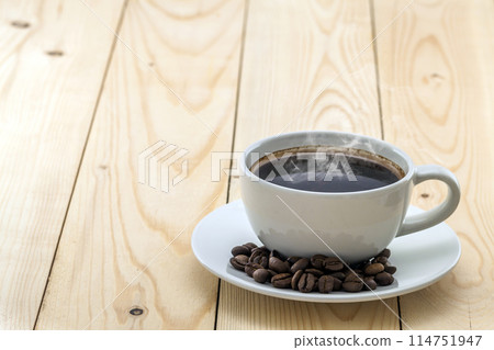 White cup with black steaming coffee on plate with coffee beans on yellow White cup with black steaming coffee on plate with coffee beans on yellow 114751947