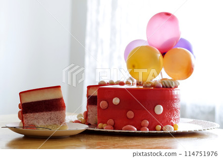 Homemade red birthday cake with air baloons. Slice of a red velvet cake on a plate. Homemade red birthday cake with air baloons. Slice of a red velvet cake on a plate. 114751976