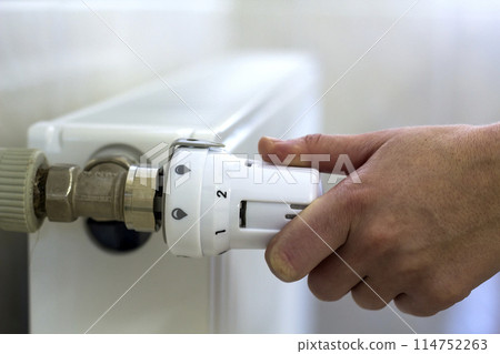 Hand adjusting the valve knob thermostat of heating radiator Hand adjusting the valve knob thermostat of heating radiator 114752263