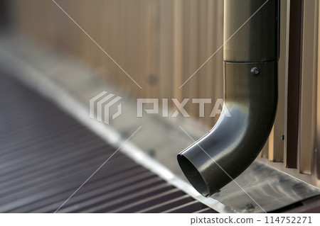 Brown new gutter metal system pipe. Vertical construction for draining rain water from building roof on the wall. Drain protection. 114752271