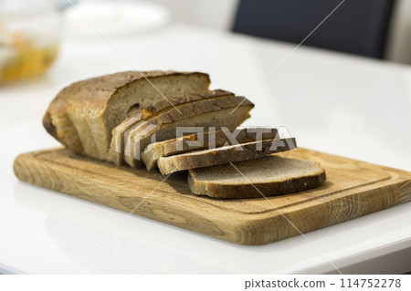 Slices of cut bread on wooden board on a table Slices of cut bread on wooden board on a table 114752278