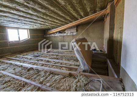 House attic under construction. Mansard walls and ceiling insulation with rock wool. Fiberglass insulation material in wooden frame for cold barrier 114752313