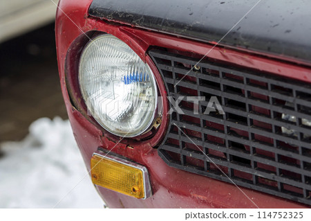 Red vintage car on a festival of old cars. Retro car's headlight close up. Red vintage car on a festival of old cars. Retro car's headlight close up. 114752325