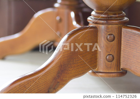 Close-up detail image of wooden table. Element of oak furnishing. Decorative wooden part of a kitchen classic table. 114752326