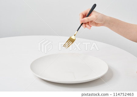 A woman's hand holding a white plate and a fork 114752463