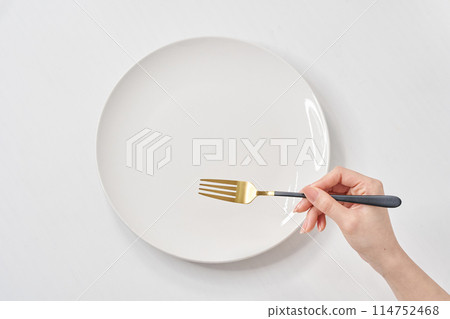 A woman's hand holding a white plate and a fork 114752468