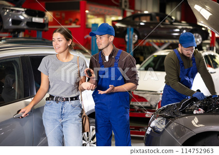 Young male mechanic giving car keys to woman client 114752963