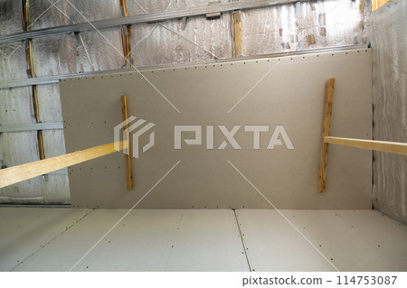 Room under construction with silver aluminum insulation foil and drywall on walls and ceiling. 114753087