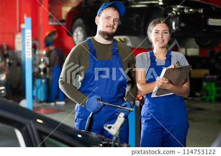 Guy and woman mechanics posing in car service 114753122
