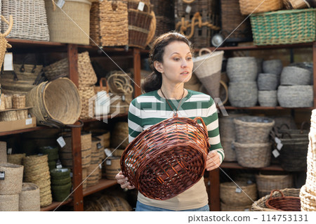 Woman choosing a wicker basket at hardware store Woman choosing a wicker basket at hardware store 114753131