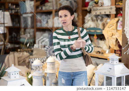 Shopper browses furniture store looking for perfect items for her garden. She carefully examines assortment on display 114753147