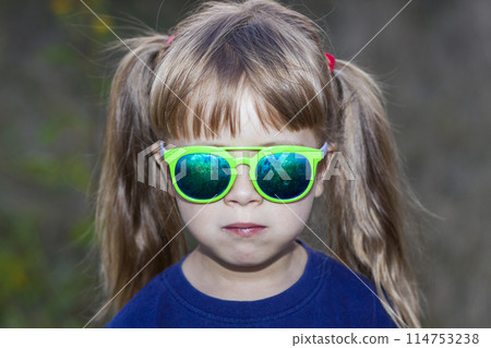 Portrait of little fashionable girl in green sunglasses outdoors Portrait of little fashionable girl in green sunglasses outdoors 114753238