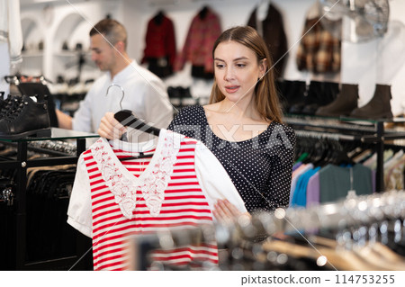 Young woman choosing blouse in clothing store 114753255