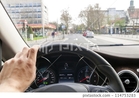 Steerind wheel with driver hand on it in modern car interior with view of street Steerind wheel with driver hand on it in modern car interior with view of street 114753283