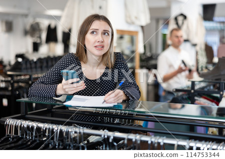 Upset girl store owner make calculations, check documents and counts budget deficit using her phone Upset girl store owner make calculations, check documents and counts budget deficit using her phone 114753344