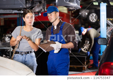 Mechanic guy signs agreement with young woman client Mechanic guy signs agreement with young woman client 114753347