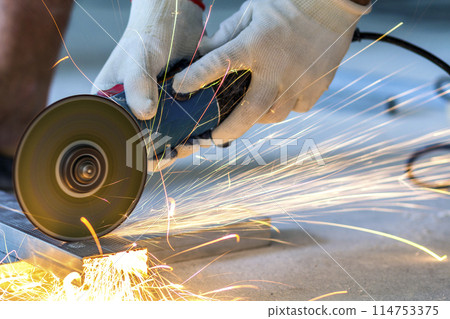 Close-up of worker cutting metal with grinder. Sparks while grinding iron. 114753375