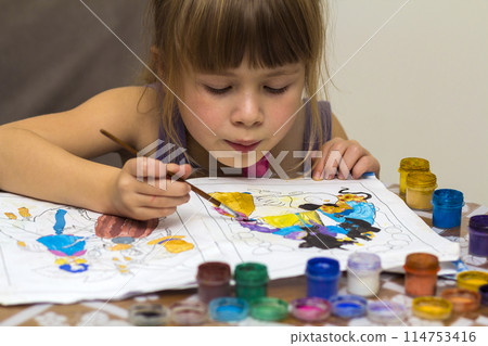 Cute little girl painting with brush and colourful paints 114753416