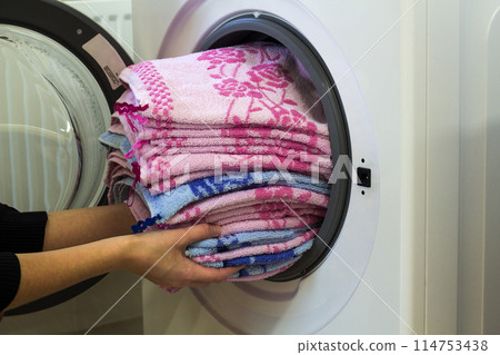 Woman hands putting laundry into washing machine at home Woman hands putting laundry into washing machine at home 114753438