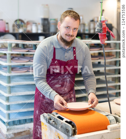 Young man polishing blanks of ceramic products 114753586