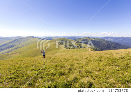 Lonely hiker standing in mountains. Tourist man enjoy mountain view Lonely hiker standing in mountains. Tourist man enjoy mountain view 114753778