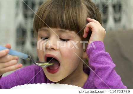 Child girl eating soup from a plate with a spoon Child girl eating soup from a plate with a spoon 114753789