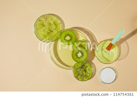 A glass cup with yellow body scrubs and a plastic stick inserted, next to a glass tray filled green essence and kiwi slices, a dish of chopped kiwi and the other with white scrubs, yellow background A glass cup with yellow body scrubs and a plastic stick inserted, next to a glass tray filled green essence and kiwi slices, a dish of chopped kiwi and the other with white scrubs, yellow background 114754381