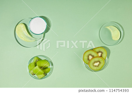 Creative photo for advertise product about exfoliation extracted from fresh kiwi, blank glass tray and vacant space on table for presentation. Photo was shot from above view, copy space Creative photo for advertise product about exfoliation extracted from fresh kiwi, blank glass tray and vacant space on table for presentation. Photo was shot from above view, copy space 114754393