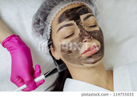 Close-up of carbon peeling procedure for middle-aged woman face. Laser pulses clean skin. Process of photothermolysis, warming, laser carbon peeling. Facial skin rejuvenation, cosmetology treatment. 114755035