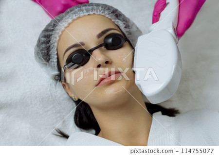 woman receiving procedure, skin rejuvenation at beauty salon. Elos procedure removes brown spots and narrows pores , smoothens fine wrinkles, slows down the age-related changes in skin. woman receiving procedure, skin rejuvenation at beauty salon. Elos procedure removes brown spots and narrows pores , smoothens fine wrinkles, slows down the age-related changes in skin. 114755077