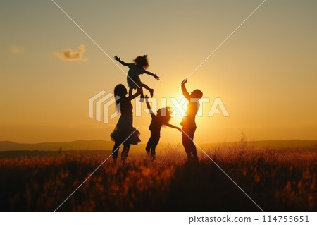 Family playing and jumping in sunset silhouette 114755651